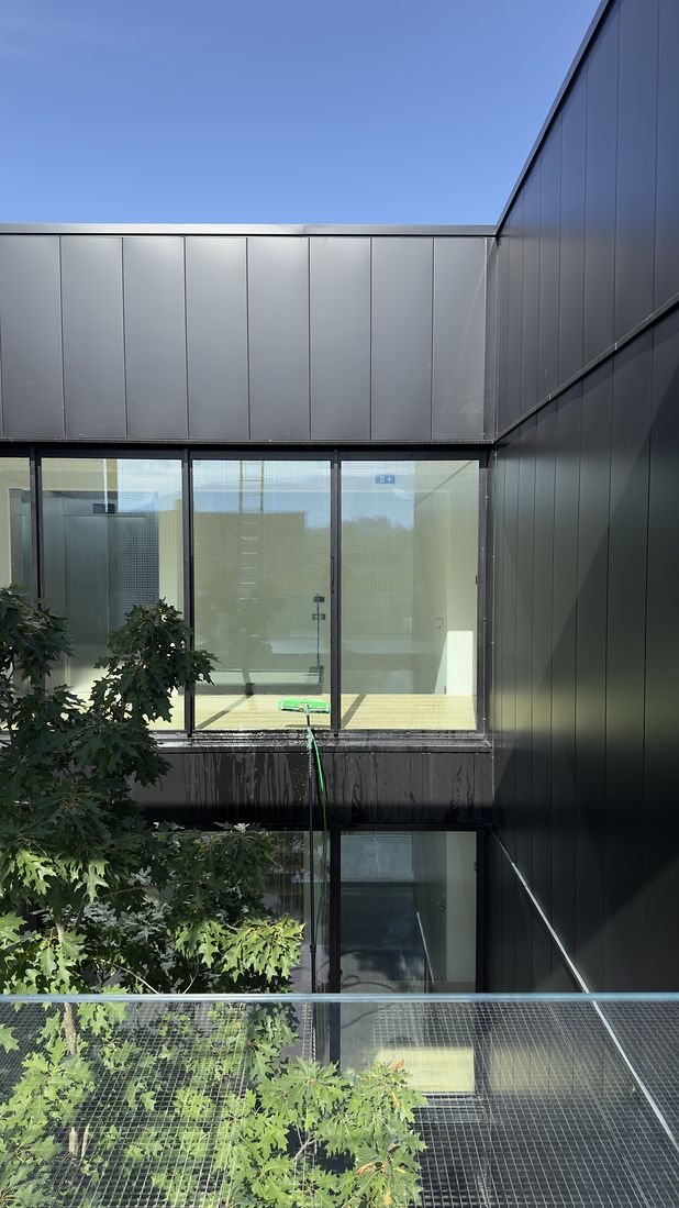 Lavage à l’eau pure des vitrages d’un bâtiment tertiaire à bardage noir